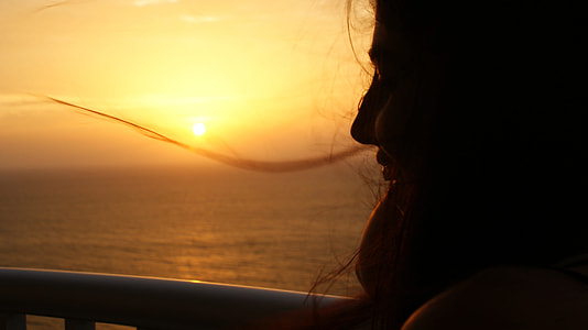 silhouette photography of woman near body of water during golden hour thumbnail