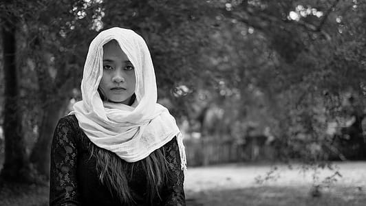 Grayscale Photo of Woman Wearing Abaya Headdress Near Tree thumbnail