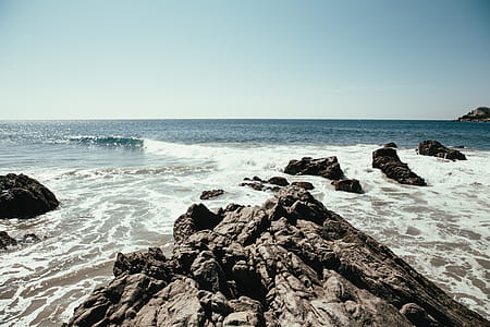 Ocean waves crashing on rocks in sunshine thumbnail