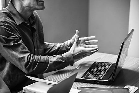 grayscale photography of man sitting on chair infront of the laptop thumbnail