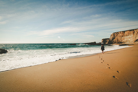 person walking towards ocean during daytime thumbnail