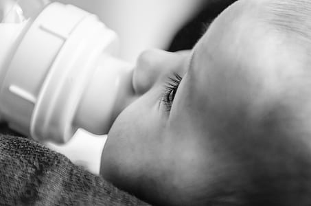 baby sipping milk in feeding bottle thumbnail