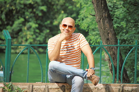 man wearing blue denim pants sitting near river thumbnail