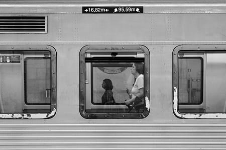 Grayscale Photography of Woman Standing Inside Train thumbnail