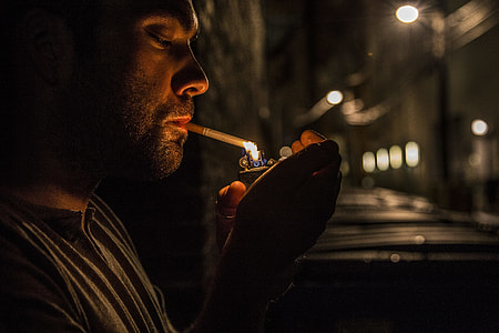 man holding lighter lighting cigarette stick thumbnail