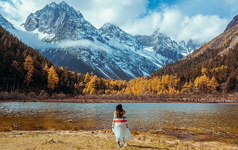 woman walking near body of water during daytime thumbnail
