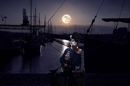 woman wearing blue 1-shoulder top sitting near body of water during nighttime thumbnail