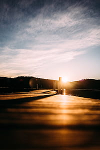 brown wooden dock near silhouette of trees at golden hour thumbnail
