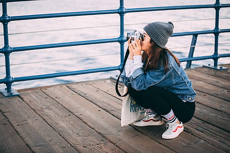 woman on wooden bridge taking picture during daytime thumbnail
