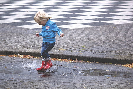 Boy in Blue Jacket Hopping on Water Puddle thumbnail