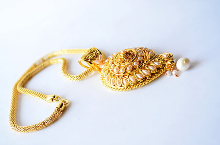 gold-colored necklace on white surface \] thumbnail