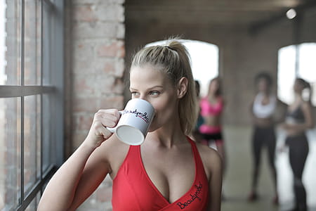 Blonde Young Woman In Red Sports Bra drinking a cup of coffee In Aerobic Dance Class thumbnail