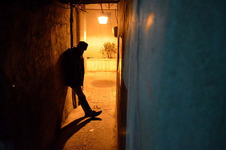 silhouette of man leaning on concrete wall with lighted pendant lamp thumbnail