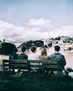 five people sitting on gray wooden bench overlooking city thumbnail