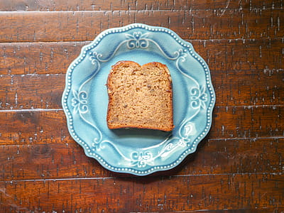 Topview of banana nut bread sitting on a blue plate in the sunlight. thumbnail