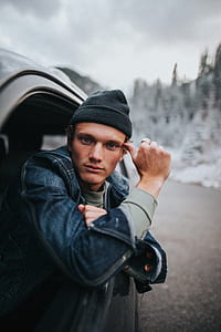 man wearing blue denim jacket and knit cap inside car thumbnail