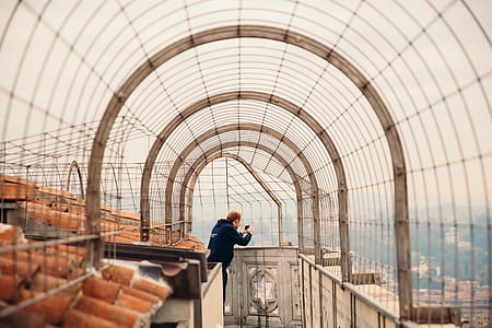 A young caucasian man taking photo with his camera on a rooftop walkway thumbnail