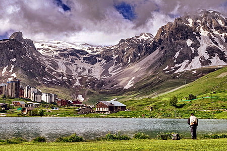 city buildings and village houses below snow-covered mountains during daytime thumbnail