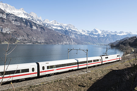 white and red train beside river and mountain thumbnail