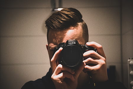 person aiming black Nikon DSLR camera thumbnail