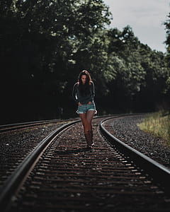 woman in gray sweater walking on train rail thumbnail