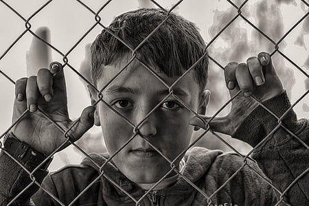 boy beside chain-linked fence thumbnail