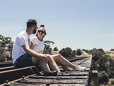 man and woman sitting on train tracks thumbnail