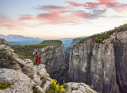 person standing in front of cliff during daytime thumbnail