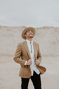 man wearing white collared shirt and brown notched lapel suit jacket standing near brown sand thumbnail