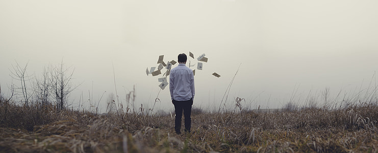 person in white shirt standing on dried grass field during cloudy weather thumbnail