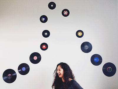 woman in black top standing and laughing nest to disc wall decors thumbnail