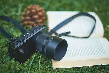 photo of black DSLR camera and white notebook on green grass thumbnail