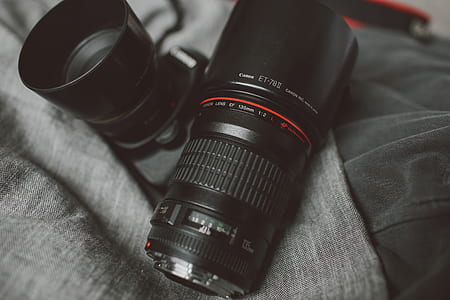 two black camera zoom lenses on gray textile thumbnail