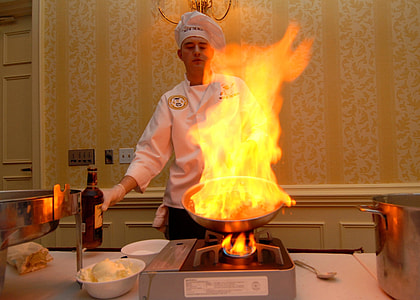chef using a frying pan lighted on fire inside kitchen thumbnail