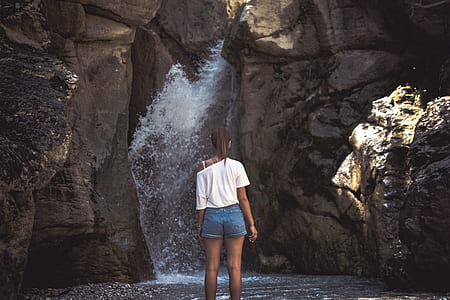 woman in white top standing in front of waterfalls thumbnail