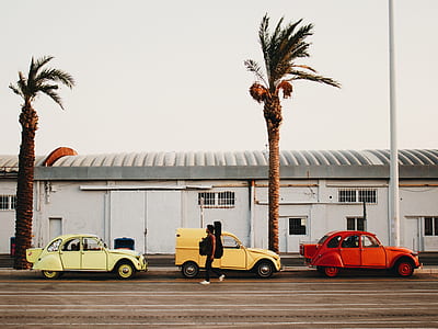 two person walking on road beside three cars thumbnail