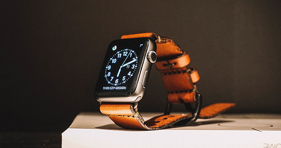 Apple Watch with brown strap on white surface thumbnail