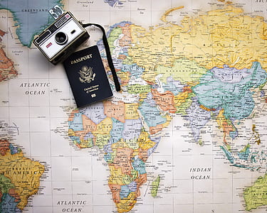 vintage grey and black camera near passport on world map thumbnail