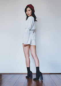 woman wearing white long-sleeved dress and red snapback cap while standing on floor thumbnail
