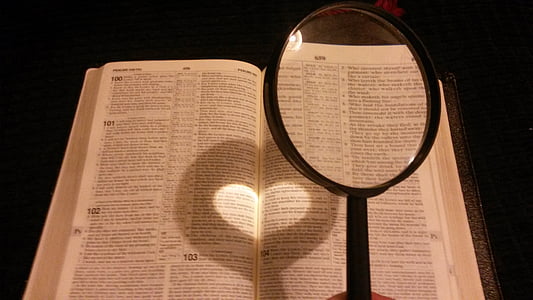 person holding black handled magnifying glass near book page thumbnail