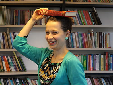 woman placing book on top of her head while smiling thumbnail