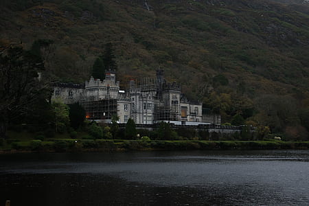 white concrete building near body of water and green trees thumbnail