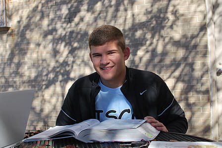 man wearing black Nike Jacket sitting while reading a book thumbnail