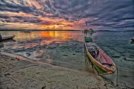 green and pink wooden canoe on seashore thumbnail