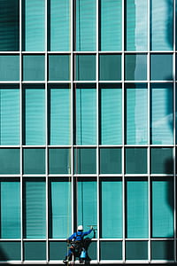 hanging man using squeegee on building mirror thumbnail