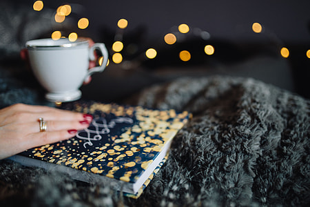Young woman at home reading Hygge book and drinking thumbnail