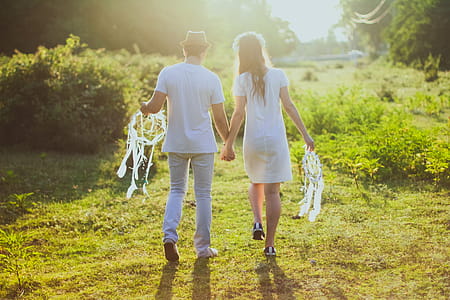 Coupe With White Dress and Suit Holding a White Dreamcatcher While Walking on Green Grass thumbnail
