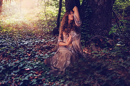 woman leaning on tree trunk during daytime thumbnail