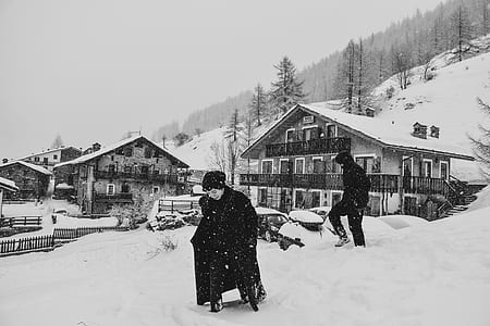 grayscale photo of person walking on field covered with snow thumbnail