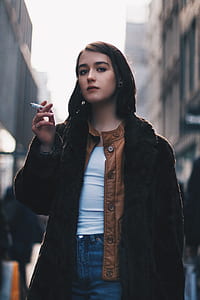 shallow focus photography of woman standing on the street smoking cigarette thumbnail
